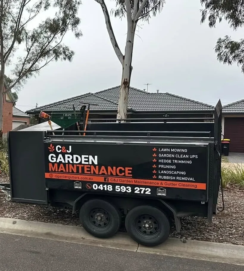 The signwritten C&J Garden Maintenance trailer parked on a job in Melbourne's west